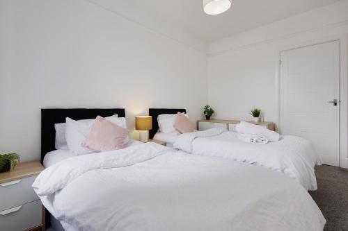 two large beds with white sheets and pink pillows at Wimbourne Road Apartment 3 in Bournemouth