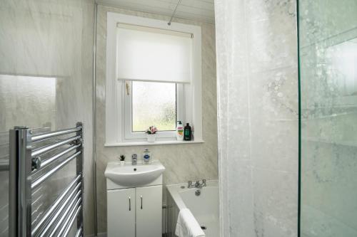 ein weißes Bad mit einem Waschbecken und einer Dusche in der Unterkunft Free Parking - 2 Bedroom Flat in Cambusnethan