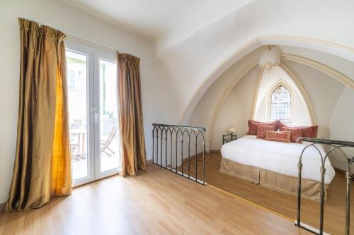 uma cama num quarto com uma janela arqueada em 66C2 Unique apartment for 6 in a castle with pool em Perpignan