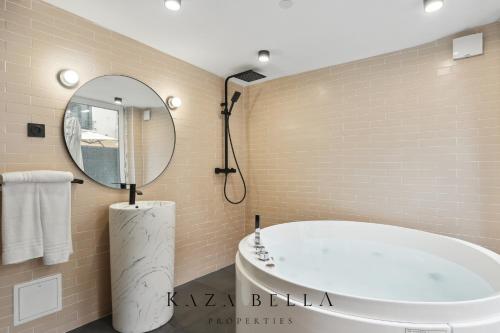 uma casa de banho com uma banheira e um espelho redondo em KAZA BELLA - Maisons Alfort 6 Luxurious little house with private garden and Jacuzzi em Maisons-Alfort