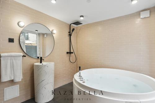 a bathroom with a tub and a round mirror at KAZA BELLA - Maisons Alfort 6 Luxurious little house with private garden and Jacuzzi in Maisons-Alfort