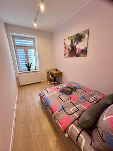 a bedroom with a bed and a desk and a window at Apartment Targowa L7 in Lublin