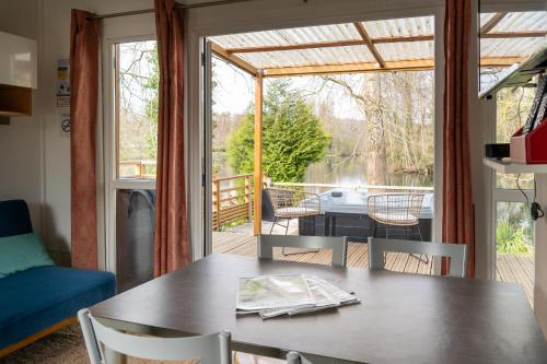 a dining room with a table and a view of a deck at Camping du Château Vert in Hondainville