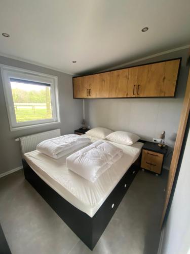 1 dormitorio con 1 cama con sábanas blancas y ventana en Chalet Rustique, en Oldeberkoop