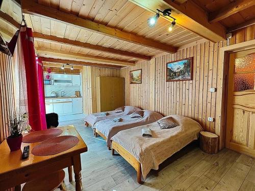 - une chambre avec 2 lits dans une pièce dotée de murs en bois dans l'établissement Sichlański Zakątek, à Murzasichle