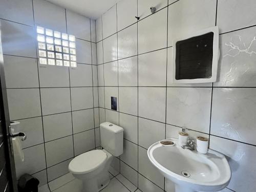 a white bathroom with a toilet and a sink at No Worries Pipa in Pipa