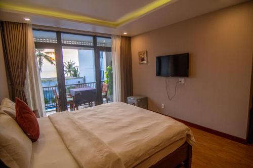 a bedroom with a bed and a television and a balcony at Sealight Villa and House Phu Quoc in Phu Quoc