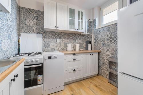 a kitchen with white cabinets and a sink at Fala 2 by Grand Apartments in Gdańsk