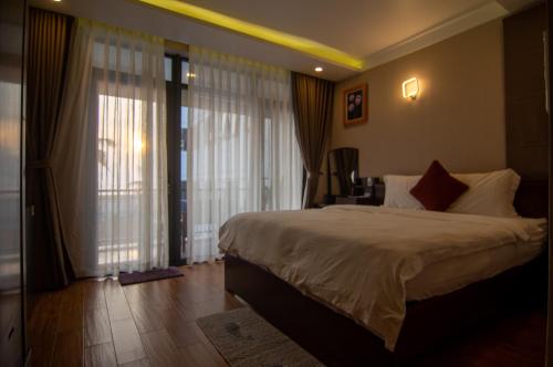 a bedroom with a large bed and large windows at Sealight Villa and House Phu Quoc in Phu Quoc