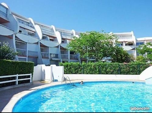 une grande piscine devant un immeuble dans l'établissement Le Dauphin - 150m de la plage - Piscine -, à La Grande Motte