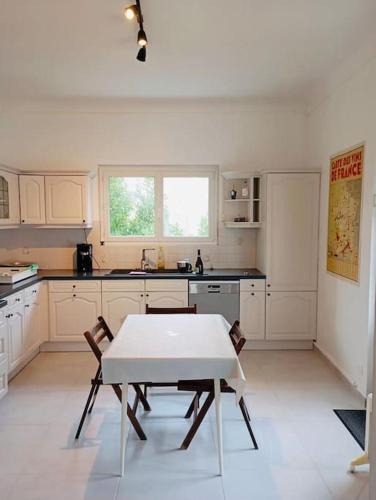une cuisine blanche avec une table et des chaises dans l'établissement Jolie Maison 6pers Wifi Billard, à Boulogne-sur-Mer