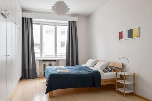 1 dormitorio con 1 cama con manta azul y ventana en WeHost Spacious 2BR in the Helsinki Center en Helsinki