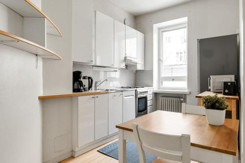 cocina con armarios blancos y mesa de madera en WeHost Spacious 2BR in the Helsinki Center en Helsinki