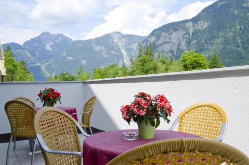 uma mesa com flores em uma varanda com montanhas em Jutel Obertraun em Obertraun