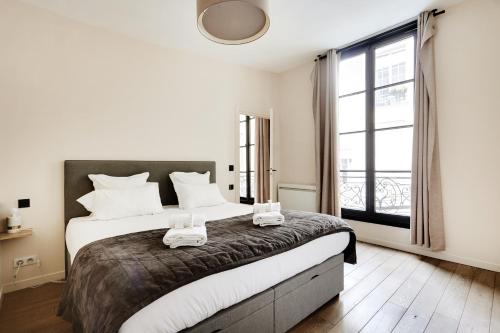 une chambre avec un grand lit et une grande fenêtre dans l'établissement Pick A Flat's Apartment in Le Marais - Rue Sainte Croix de la Bretonnerie, à Paris