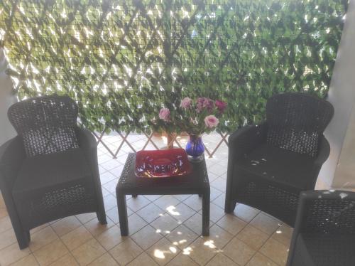 a table with a vase of flowers sitting between two chairs at Dreams House Paola-luxury suite near airport in Fiumicino