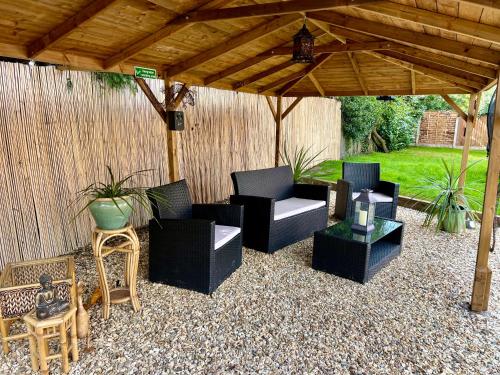 a patio with chairs and tables under a wooden pergola at Stratford-upon-Avon 4BR Family Mansion on 1 acre with Pool, Gym & BBQ! in Henley in Arden