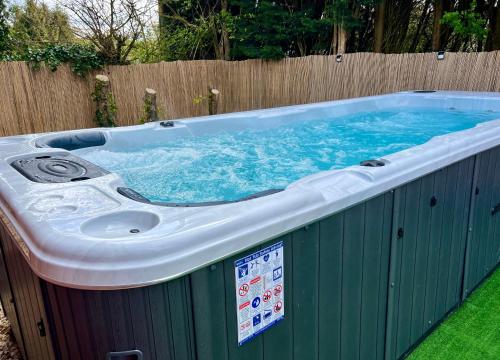 a large hot tub in a yard with a fence at Stratford-upon-Avon 4BR Family Mansion on 1 acre with Pool, Gym & BBQ! in Henley in Arden