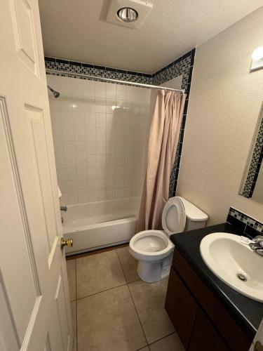 a bathroom with a toilet and a tub and a sink at Airport Motel in Pasco