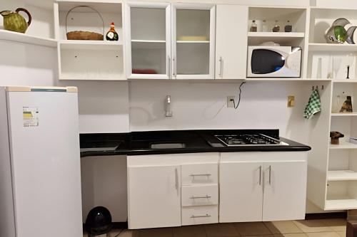 a kitchen with white cabinets and a refrigerator at Prédio à beira-mar, na melhor localização do Rio Vermelho. in Salvador