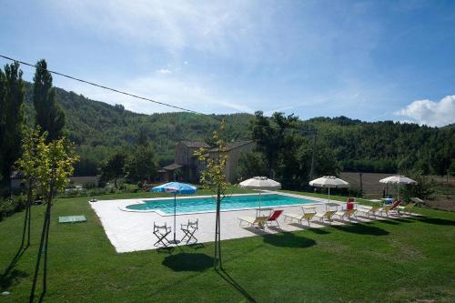 uma piscina com um monte de cadeiras e guarda-sóis em Agriturismo Verziere em Fermignano