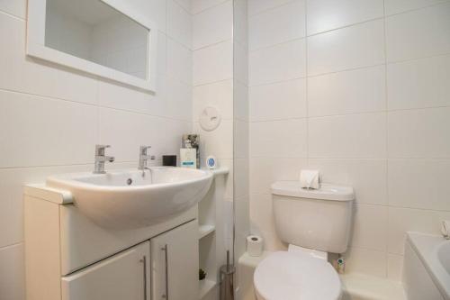 uma casa de banho branca com um lavatório e um WC em 2 bed flat near airport &parking em Paisley
