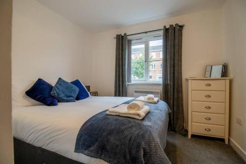um quarto com uma cama com almofadas azuis e uma janela em 2 bed flat near airport &parking em Paisley
