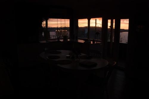 Golden Fjord-View في بيرغِن: طاولة في غرفة مظلمة مع إطلالة على غروب الشمس