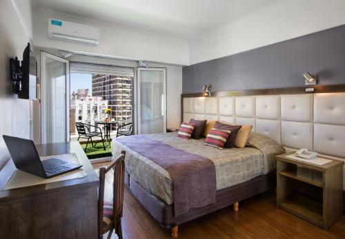 a bedroom with a bed and a desk with a laptop at Hotel Impala in Buenos Aires