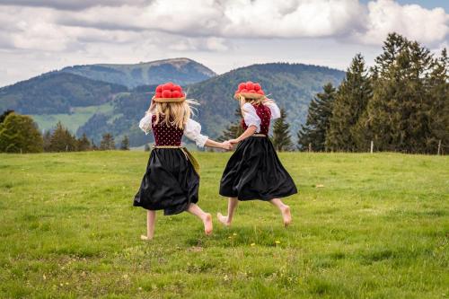 two young girls in dresses are playing in a field at Apartment 16 - Ferienresidenz Roseneck, Galeriewohnung, mit Schwimmbad in Todtnauberg bei Feldberg in Todtnauberg