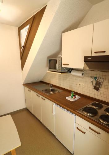 a small kitchen with white cabinets and a sink at Apartment 17 - Ferienresidenz Roseneck, Galeriewohnung, mit Schwimmbad in Todtnauberg bei Feldberg in Todtnauberg