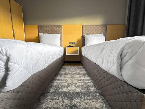 2 letti con coperte e cuscini bianchi in una stanza di acacus hotel a Kigali
