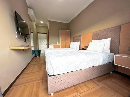 ein Schlafzimmer mit einem großen Bett und einem TV in der Unterkunft acacus hotel in Kigali