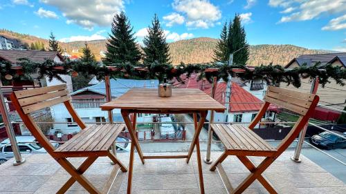 a wooden table and two chairs on a balcony at Valea Albă View - SELF CHECK-IN in Buşteni