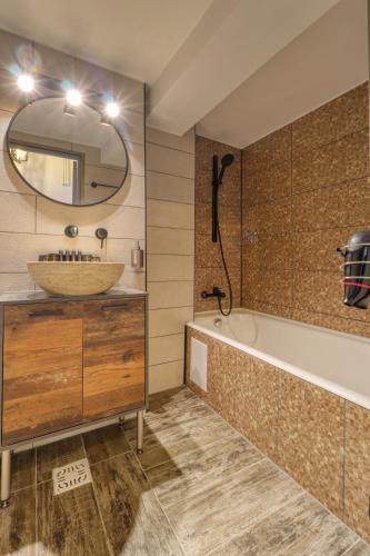 a bathroom with a sink and a tub and a mirror at RDI Elegance Apartment Downtown in Bucharest