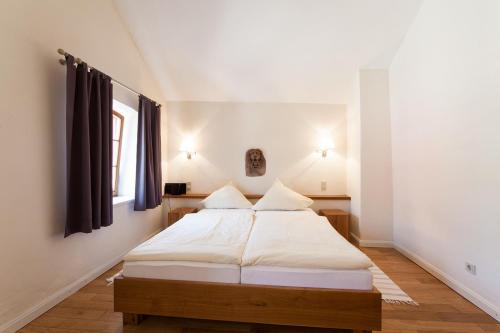 a bedroom with a bed with white sheets and a window at Weingut & Gästehaus GiwerGreif in Wasserliesch