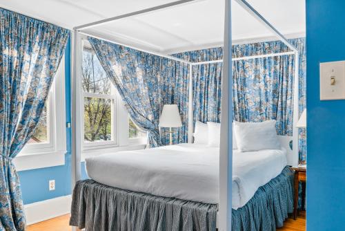 a bedroom with a bed with blue walls and windows at Beekman Arms and Delamater Inn in Rhinebeck