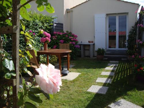 a garden with a table and a pink flower at MER à pied Vrai lit LINGE FOURNI Jardin LOCAL vélos in Brétignolles-sur-Mer