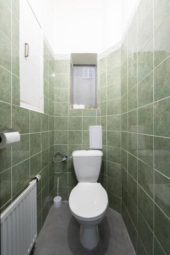 a bathroom with a toilet and a green tiled wall at Prague - Karlin Apartments in Prague