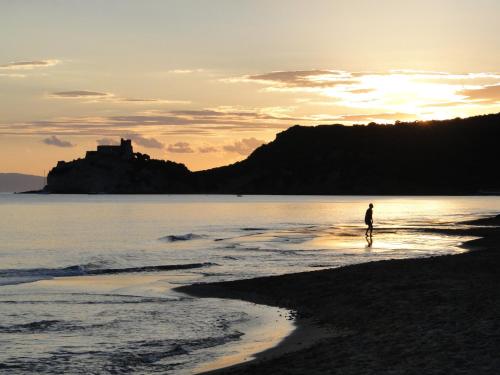 a person walking on the beach at sunset at Sunset Villa in Castiglione della Pescaia
