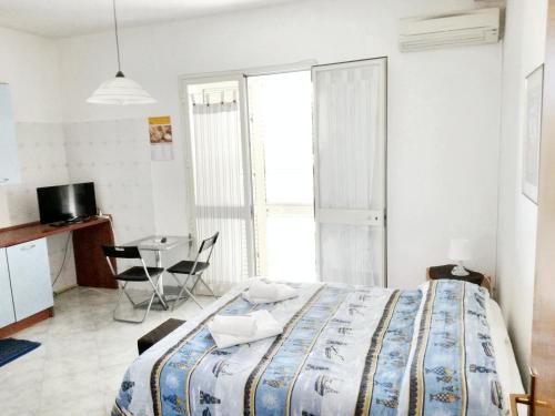 a bedroom with a bed and a table and a kitchen at Studio with sea view furnished balcony and wifi at Marsala 1 km away from the beach in Marsala