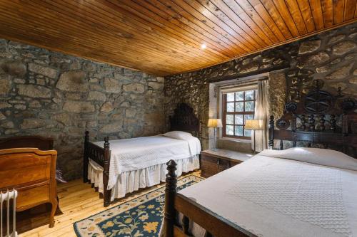 um quarto com 2 camas e uma parede de pedra em Casa da Pedra Cavalgada em Braga