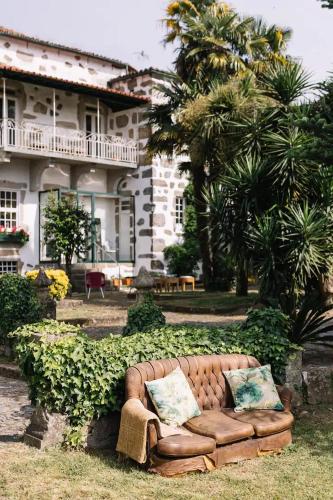 a couch sitting in the grass in front of a house at Casa da Pedra Cavalgada in Braga