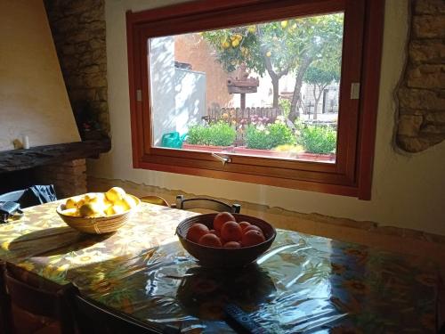 een tafel met twee fruitschalen en een raam bij Su Mulinu 