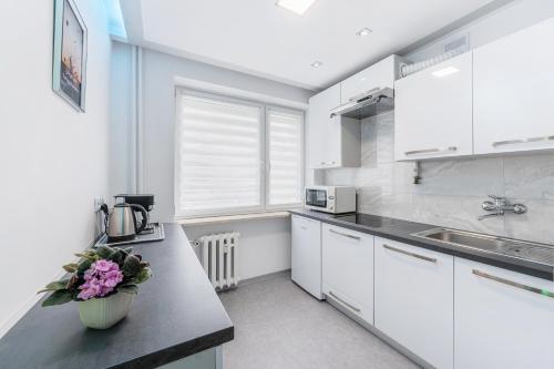 a kitchen with white cabinets and a vase of flowers on a counter at APARTAMENT PARKOWY UL. RACLAWICKA in Krakow