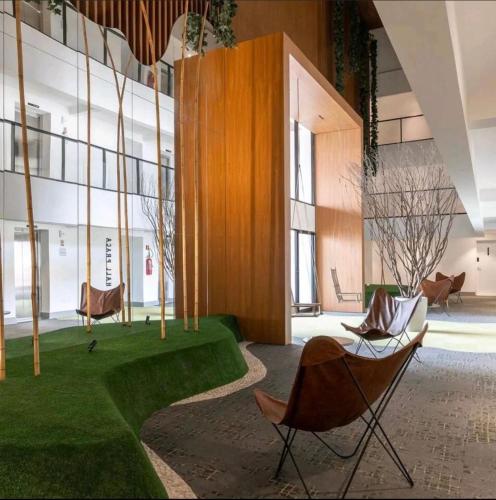 a lobby with chairs and grass in a building at Lindo flat em prédio luxuoso - Excelente localização in Goiânia