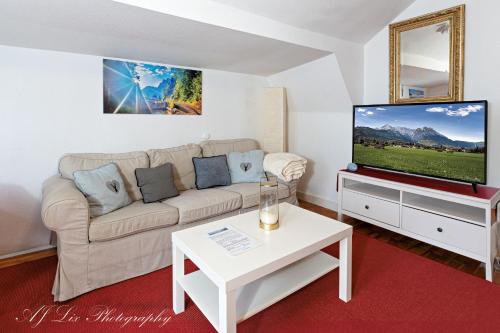 a living room with a couch and a tv at Pension Karner in Mittenwald