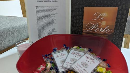 un bol rouge de nourriture sur une table avec un verre d'eau dans l'établissement Le Porto T3 55m2 vue mer immeuble traditionnel en pierre de taille avec prestations exceptionnelles barbecue ordinateur vidéosurveillance terrasse panoramique, à Porto Ota