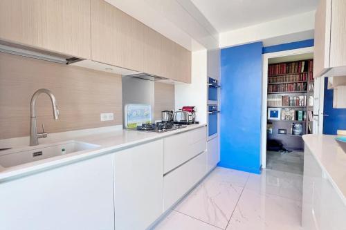 une cuisine avec des armoires blanches et un mur bleu dans l'établissement La Baia Dei Ange, à Nice