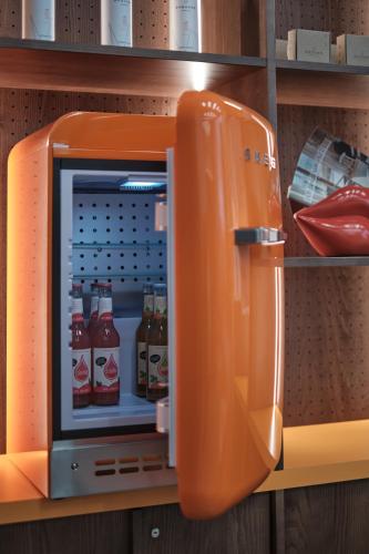 an orange refrigerator with drinks inside of it at The Zipper Hotel und Apartments in Düsseldorf